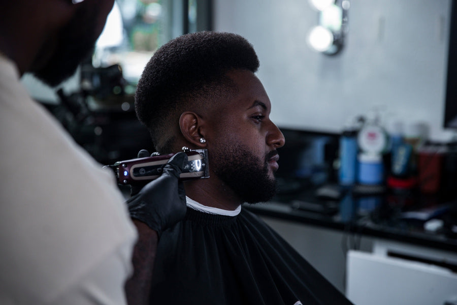 Clippers working a client's low fade, seen from the side